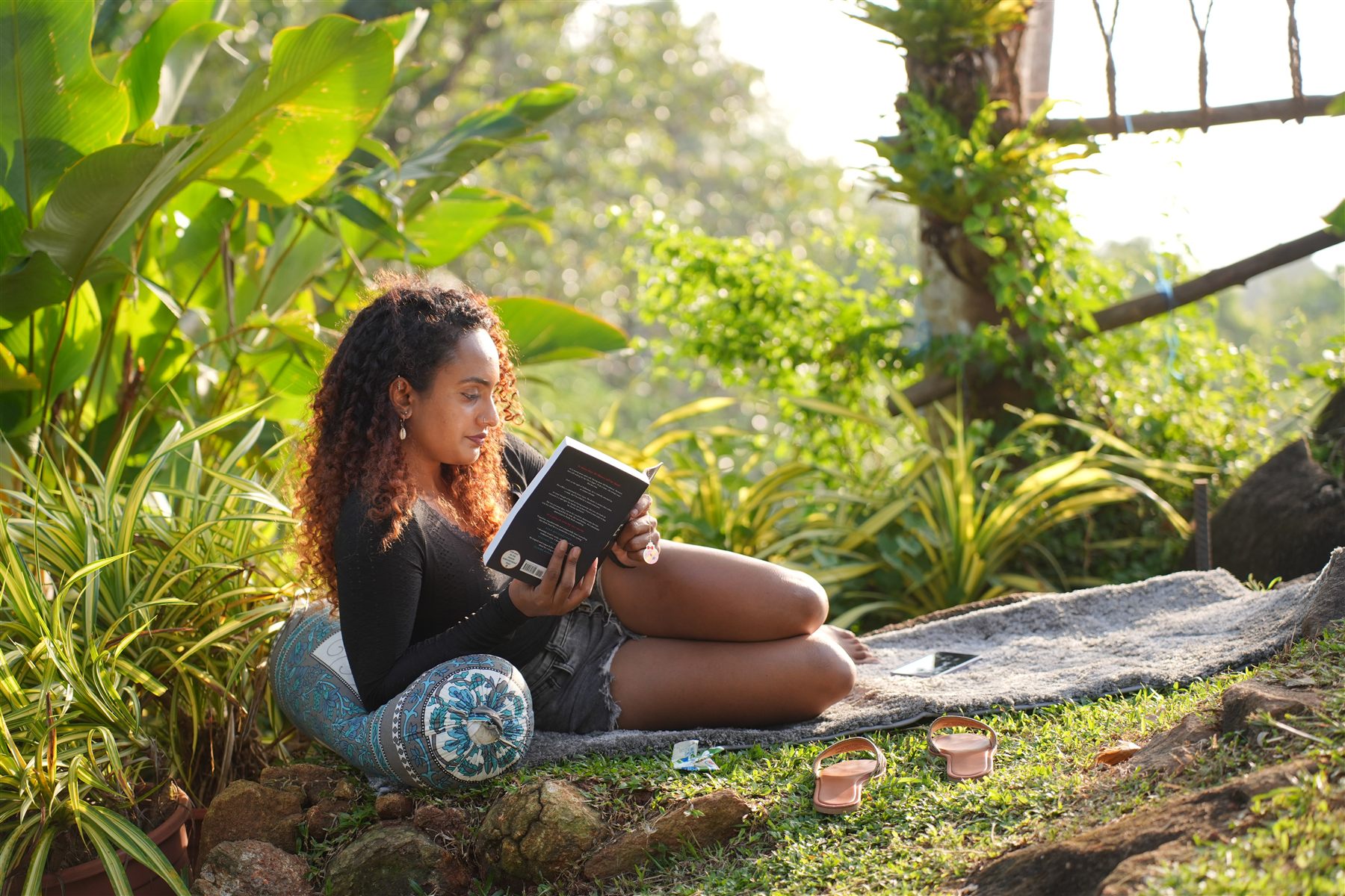 A guest reading on a rug in the sunlit garden