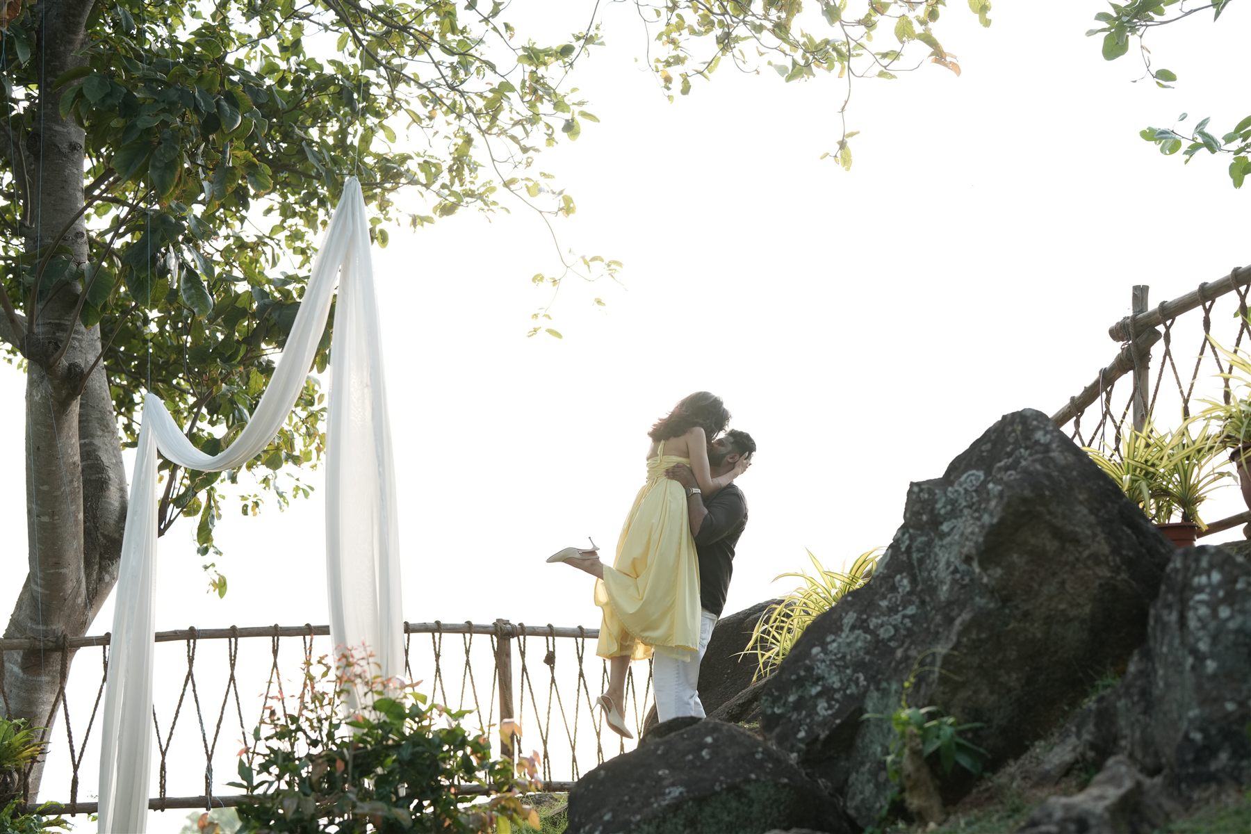 A couple embracing beside the draped tree on the cliff edge