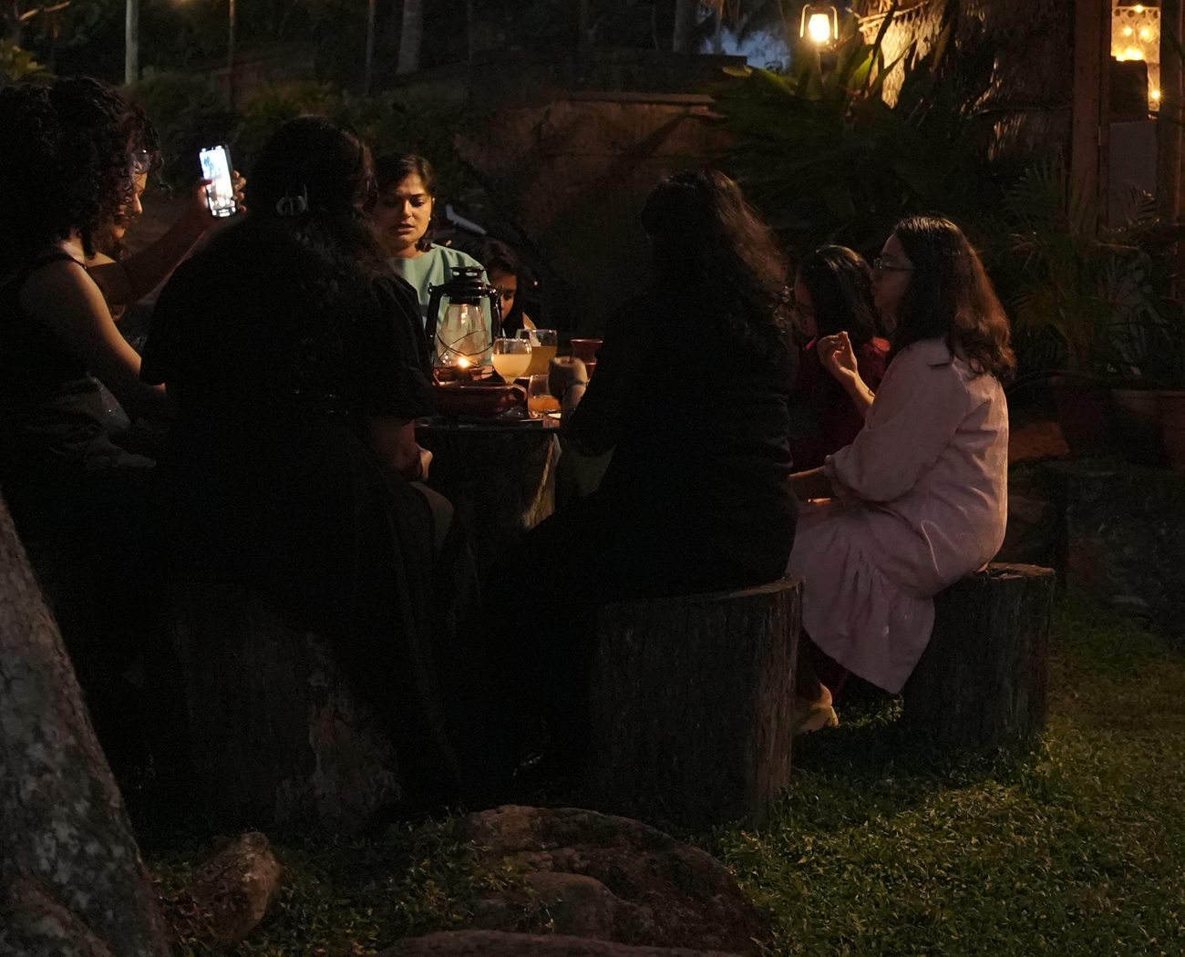 Friends at a lantern lit table in the garden after dark